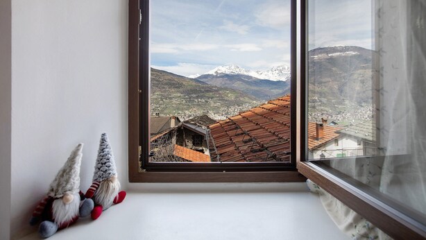 A window with a view of a mountainous landscape and a village below. - Holiday Apartment 'Da Lule' with Mountain View, Balcony and Wi-Fi (Charvensod)