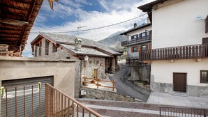A narrow street with stone buildings, a wooden fence, and a metal gate. - Holiday Apartment 'Da Lule' with Mountain View, Balcony and Wi-Fi (Charvensod)