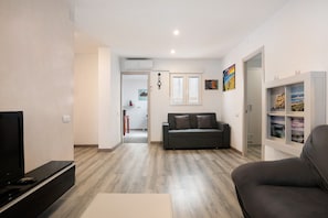 A modern living room with a flat-screen TV, a sofa, a coffee table, and a bookshelf. - Apartment 'Piso Pablo' with Private Terrace and Wi-Fi (Barbate)