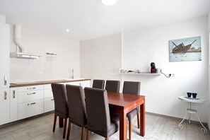 A modern kitchen with white cabinets, a wooden dining table, and four chairs. - Apartment 'Piso Pablo' with Private Terrace and Wi-Fi (Barbate)