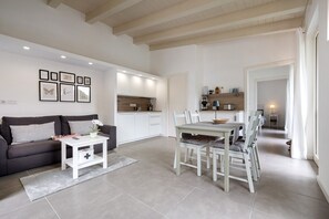 Un salon moderne comprenant un canapé, une table basse, une table à manger et des chaises. Il y a également un coin cuisine avec des placards et un plan de travail.
