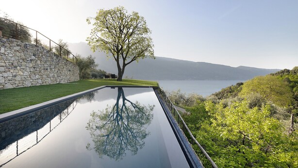 Eine Steinsäule, ein Baum und ein Gewässer.