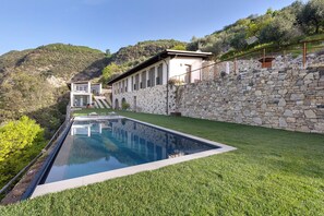 A modern house with a swimming pool, stone walls, and a view of a hillside. - Holiday Apartment "Ca' Scaì Agrifugium Olivia" with Lake View, Shared Pool and Wi-Fi (Tignale)