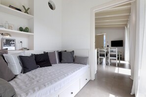 Un dormitorio con cama, mesitas de noche, televisión y un comedor con sillas y mesa.