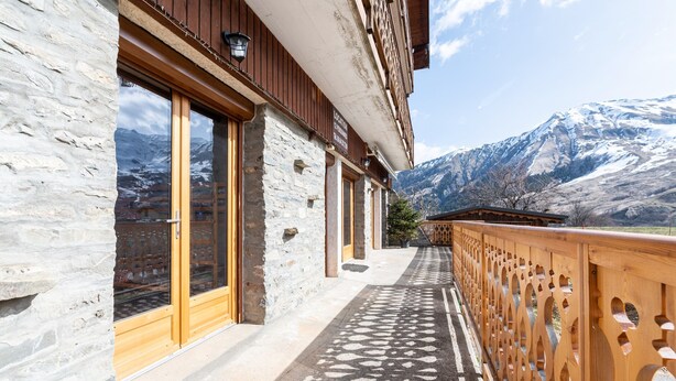 A stone building with large windows, a wooden balcony, and a mountainous backdrop. - Apartment "Albiez Montrond" with Mountain View, Balcony and Wi-Fi (Albiez-Montrond)