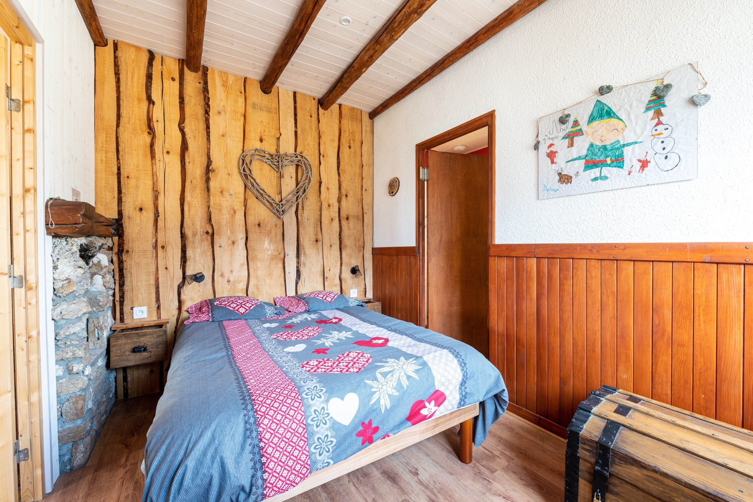 Une chambre avec un lit en bois, un mur en pierre, un banc en bois et un élément décoratif mural.