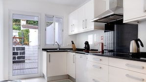 Een moderne keuken met witte kasten, een zwart aanrecht en een vaatwasser.