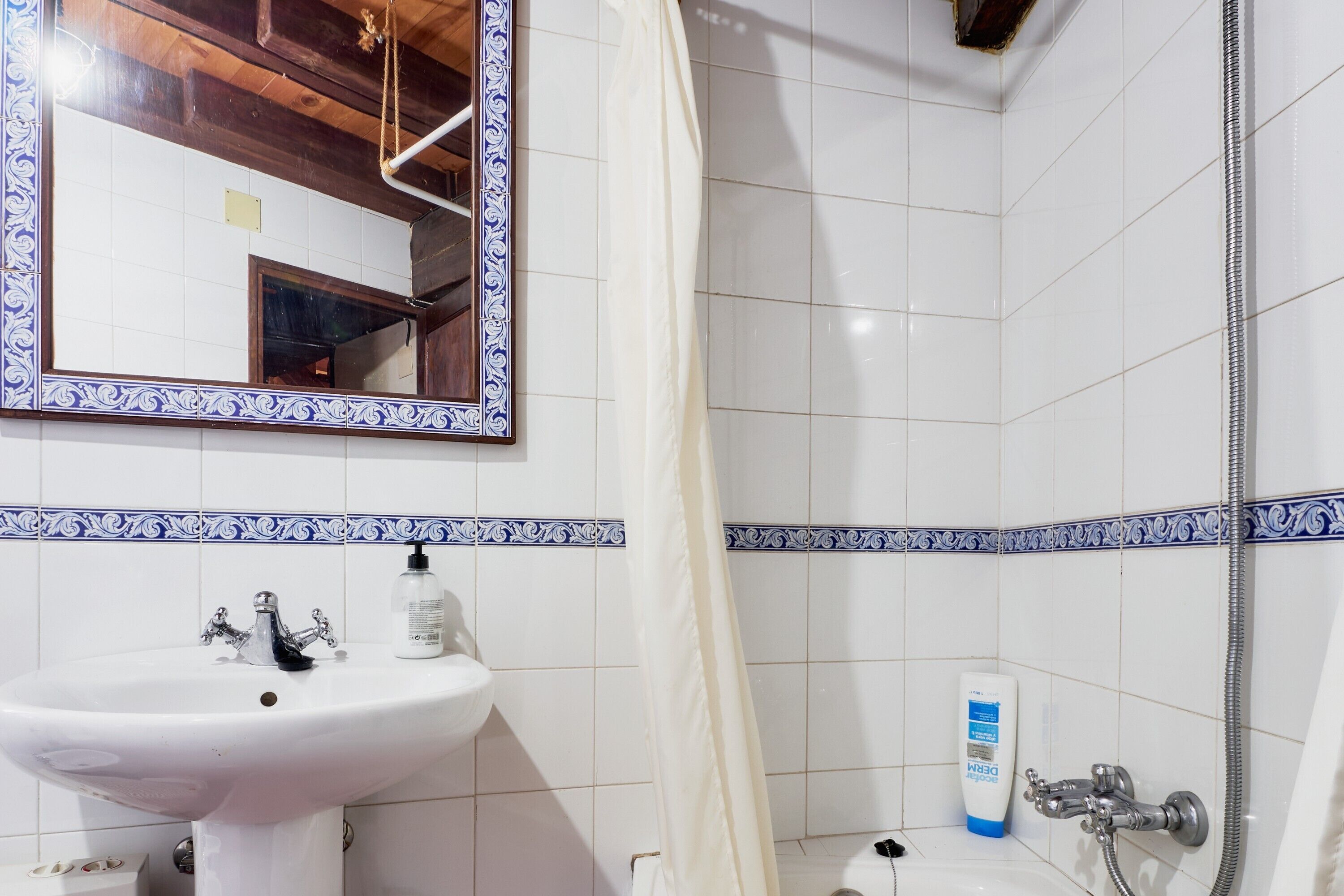 Une salle de bain avec un lavabo blanc, un miroir et une douche.