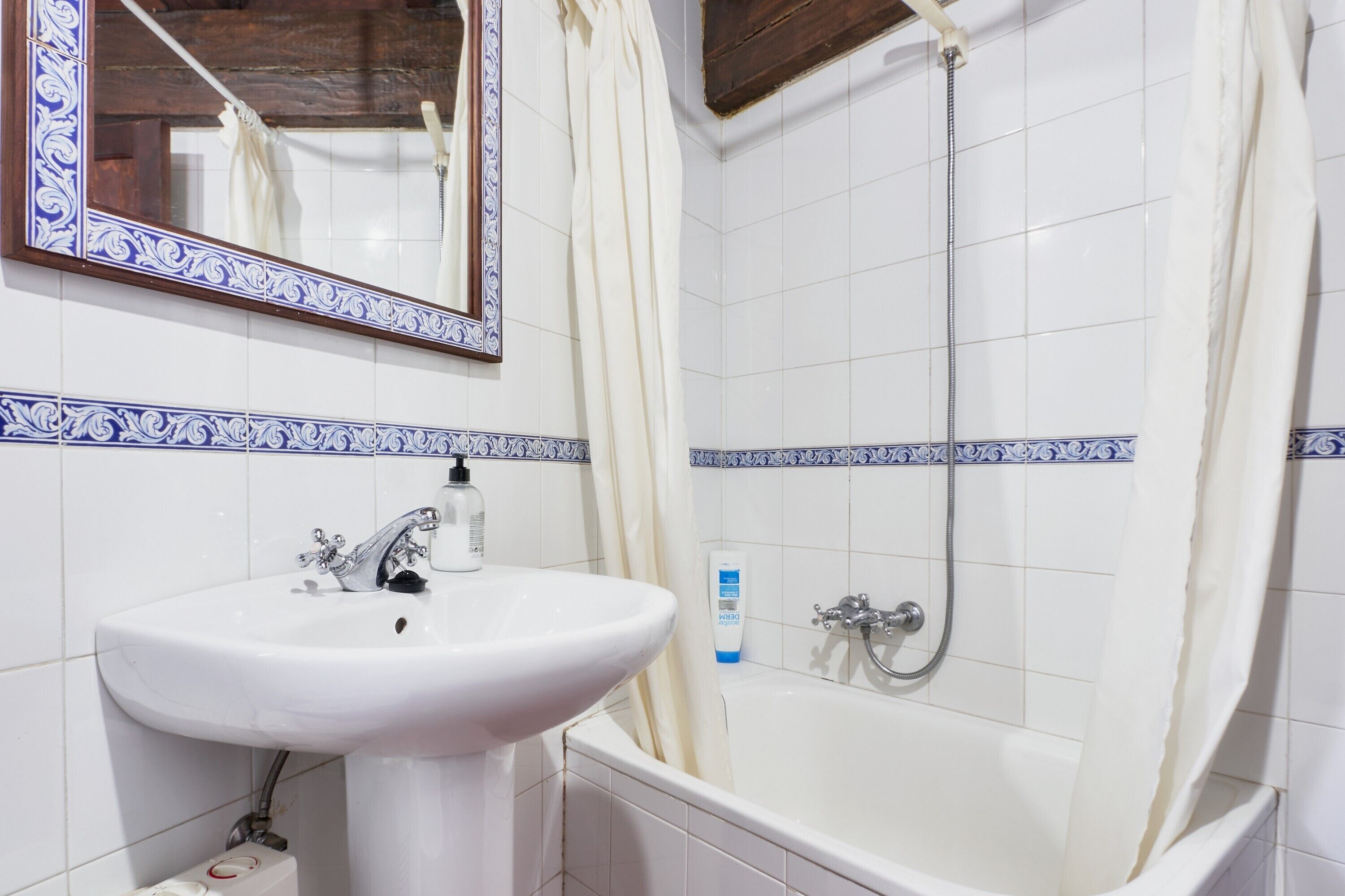 Un bagno con lavandino, specchio e vasca da bagno bianchi.