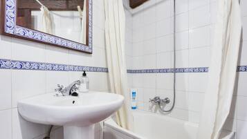 Un bagno con lavandino, specchio e vasca da bagno bianchi.