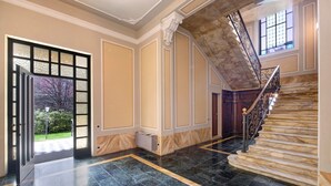 A grand hallway with a marble staircase, a large open door leading outside, and a view of the outdoors. - Apartment 'Historia Suite Bellagio' with Lake View, Shared Garden and Wi-Fi (Bellagio)