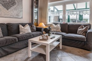 A living room with two grey sofas, a white coffee table, and a window with lace curtains. - 50005 Ferienhaus Louis - Die Doppelhaushälfte mit ca. 78qm Kann mit bis zu 6 Personen und Einem (Wittmund)