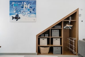 Une pièce comprenant un meuble de rangement en bois, un tableau et un canapé gris.