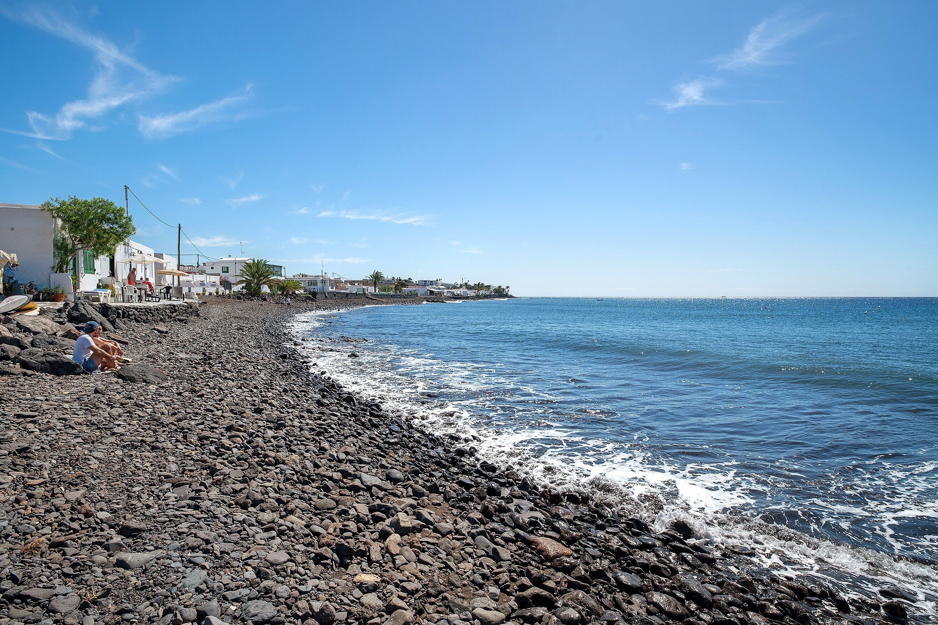 Una playa rocosa con edificios al fondo.