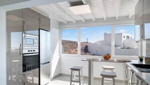 Una cocina moderna con horno empotrado, un comedor con taburetes y grandes ventanales que ofrecen vistas del paisaje.