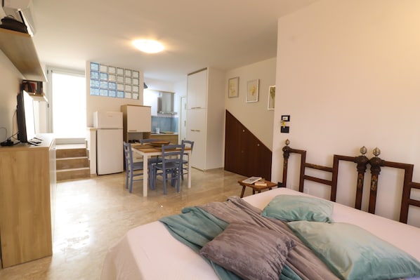 A bedroom with a bed, a desk, and a chair in the background.