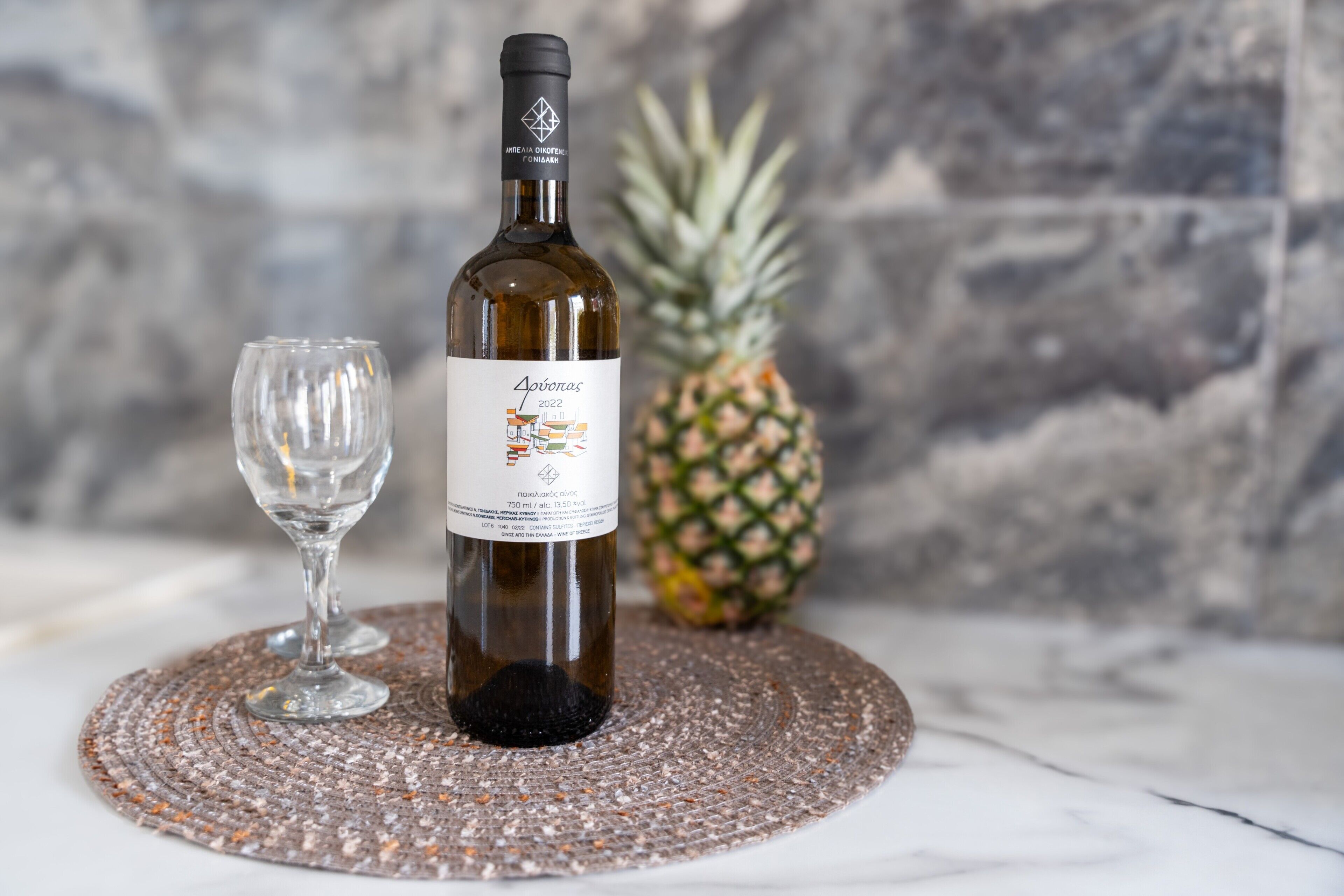 Une bouteille de vin et un verre posés sur un set de table en fibres tressées.