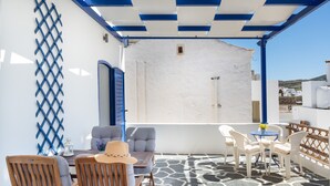 Une terrasse extérieure avec des chaises en bois, une table et un sol à motifs bleus et blancs.