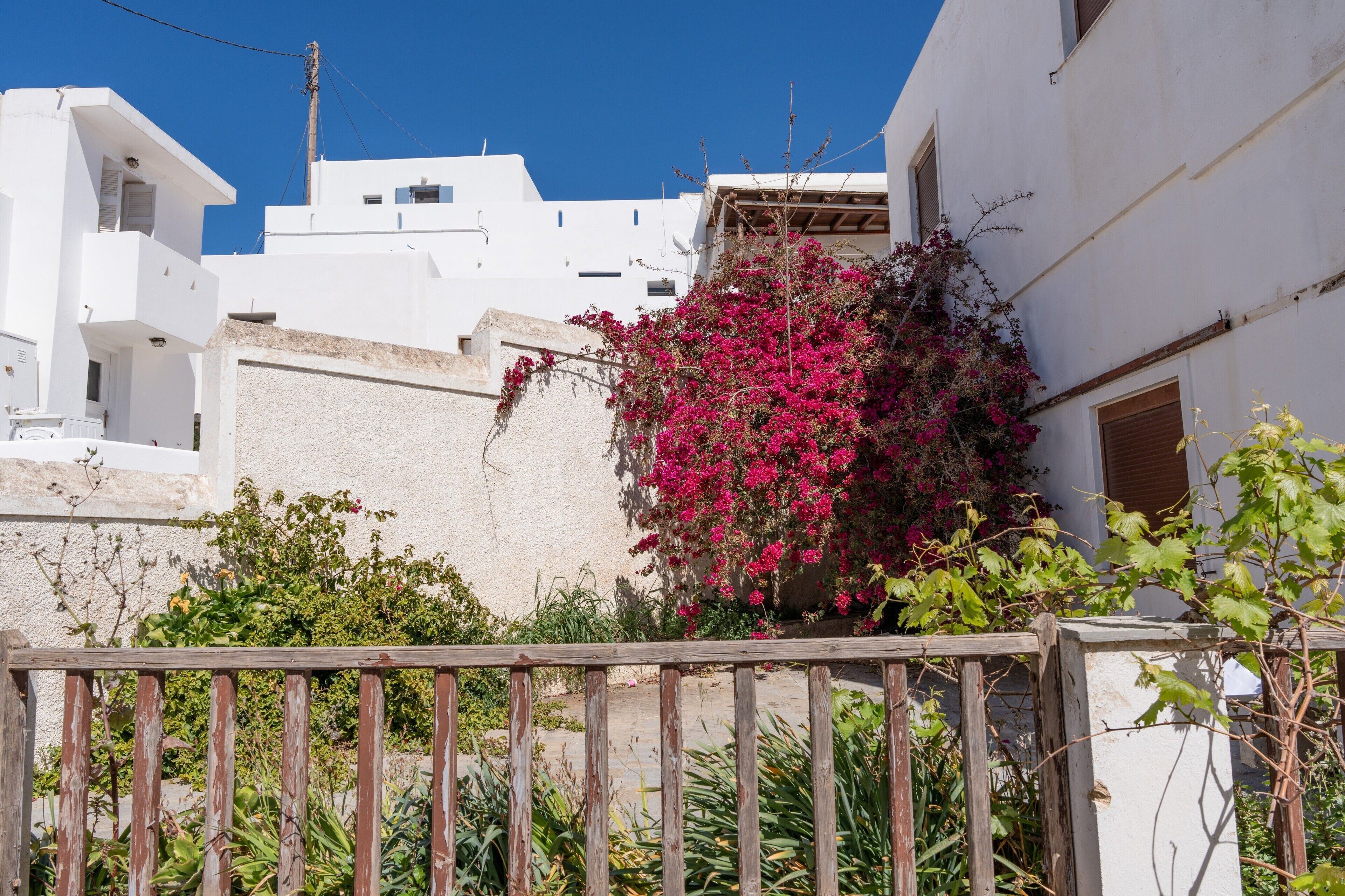 A white building with a balcony and a wooden fence in the foreground.