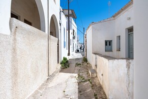 Un estrecho callejón entre edificios blancos con arcos y un cielo azul despejado.
