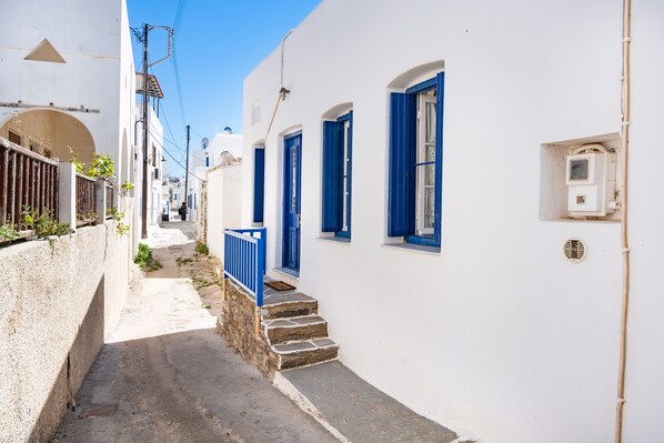 A narrow street with white buildings and blue doors, leading to a staircase.