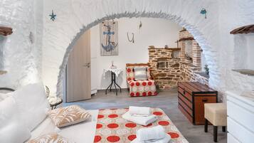 Ein gemütliches Zimmer mit einem Bett, einer Kommode, einem kleinen Tisch und einer Steinwand.