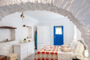 A room with a bed, a dresser, a blue door, and a white wall.