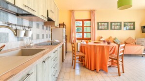 Une cuisine comprenant un coin repas, des meubles de rangement en bois, un évier et une table avec des chaises.