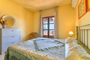 A bedroom with a bed, a dresser, a chair, a lamp, and a window with curtains.
