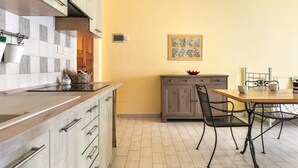 Een keuken met een houten aanrecht, kastjes, een eettafel met stoelen, en een foto aan de muur.