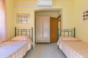 A room with two beds, a wardrobe, an air conditioner, and a framed picture on the wall. - Holiday Home 'Merlo Casa Vai' with Sea View, Wi-Fi and Air Conditioning (Zanca)