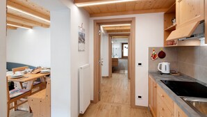 Una cocina con armarios de madera, una estufa negra y una zona de comedor con una mesa y sillas.