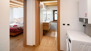 Un dormitorio moderno con techo de madera, una cama, una mesita de noche y un buró.
