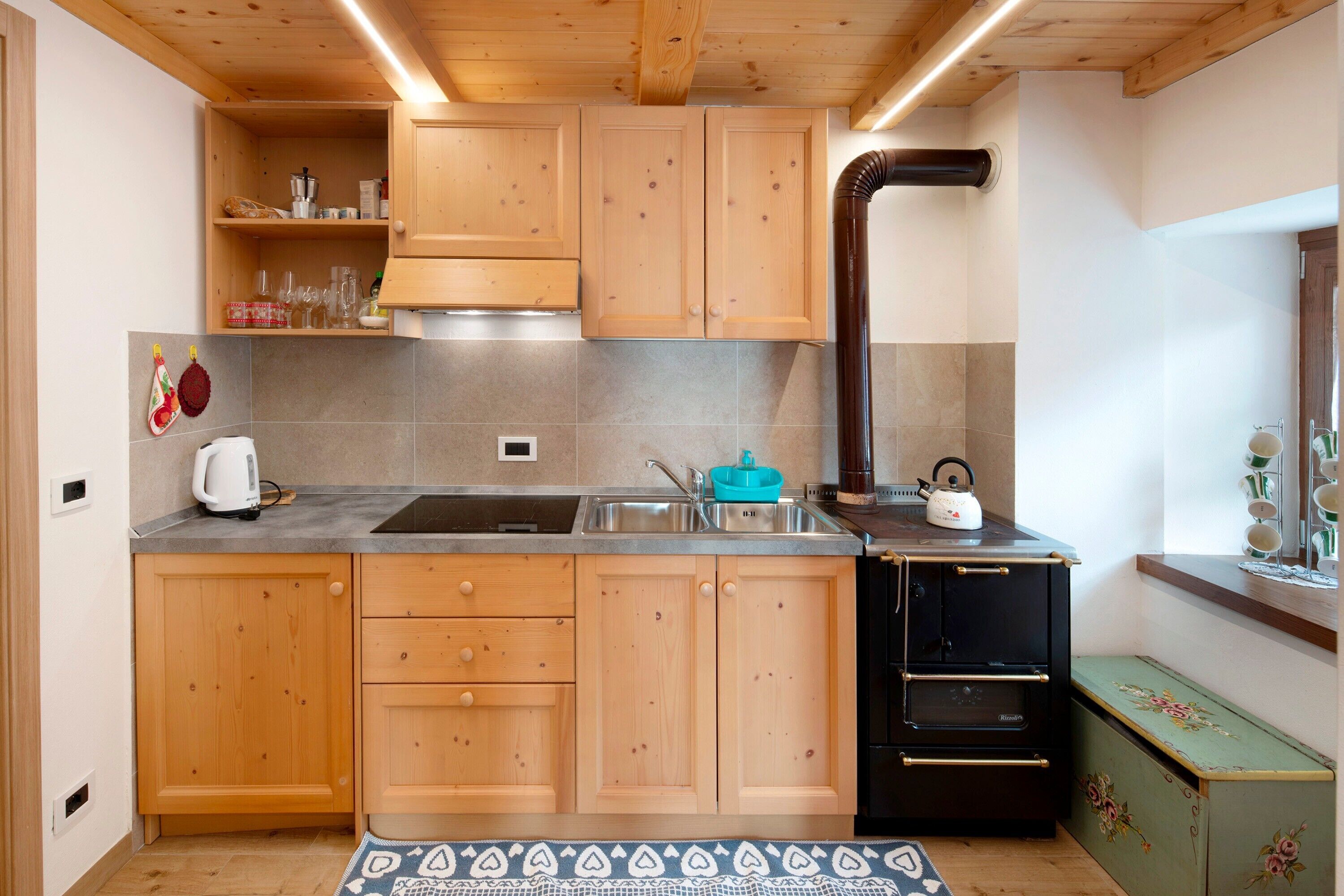 A compact kitchen with wooden cabinets, a black stove, and a sink.