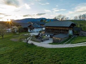 Un paisaje rural con una casa de campo, un pequeño edificio blanco y un granero de madera.