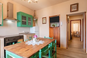 A kitchen with a wooden table, green chairs, a stove, and a green cabinet.