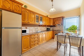 Una cocina con armarios de madera, un refrigerador, un microondas, una estufa y una mesa de comedor con sillas.
