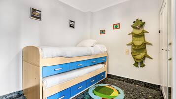 Een kinderstapelbed met lades, een kleedje en een wanddecoratie.