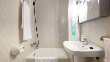 Une salle de bain équipée d’une baignoire, d’un lavabo, d’un porte-serviettes et d’un support à papier toilette.
