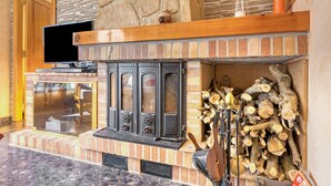 Ein Kamin mit Steinwand, einem Holzboden und einem Fernseher auf einem Schrank.