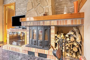 A fireplace with a stone wall, a wooden mantel, and a television on a stand.