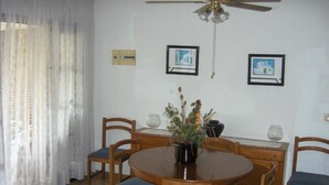 A dining area with a round wooden table, six chairs, a vase with flowers, and two framed pictures on the wall. - Holiday Home 'Villa Consuelo' with Shared Pool, Private Terrace and Private Garden (Cambrils)