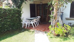 A patio with a table and chairs, a small garden area, and a building with a window and door. - Holiday Home 'Villa Consuelo' with Shared Pool, Private Terrace and Private Garden (Cambrils)