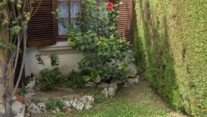 A garden with a window, a hedge, and a stone wall. - Holiday Home 'Villa Consuelo' with Shared Pool, Private Terrace and Private Garden (Cambrils)