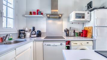 Een moderne keuken met een vaatwasser, magnetron en oven, een raam en een spoelbak.