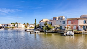 A waterfront property with buildings, a dock, and a calm water body. - 'Petite Maison Aigues Mortes' with Sea View, Shared Pool and Wi-Fi (Aigues-Mortes)