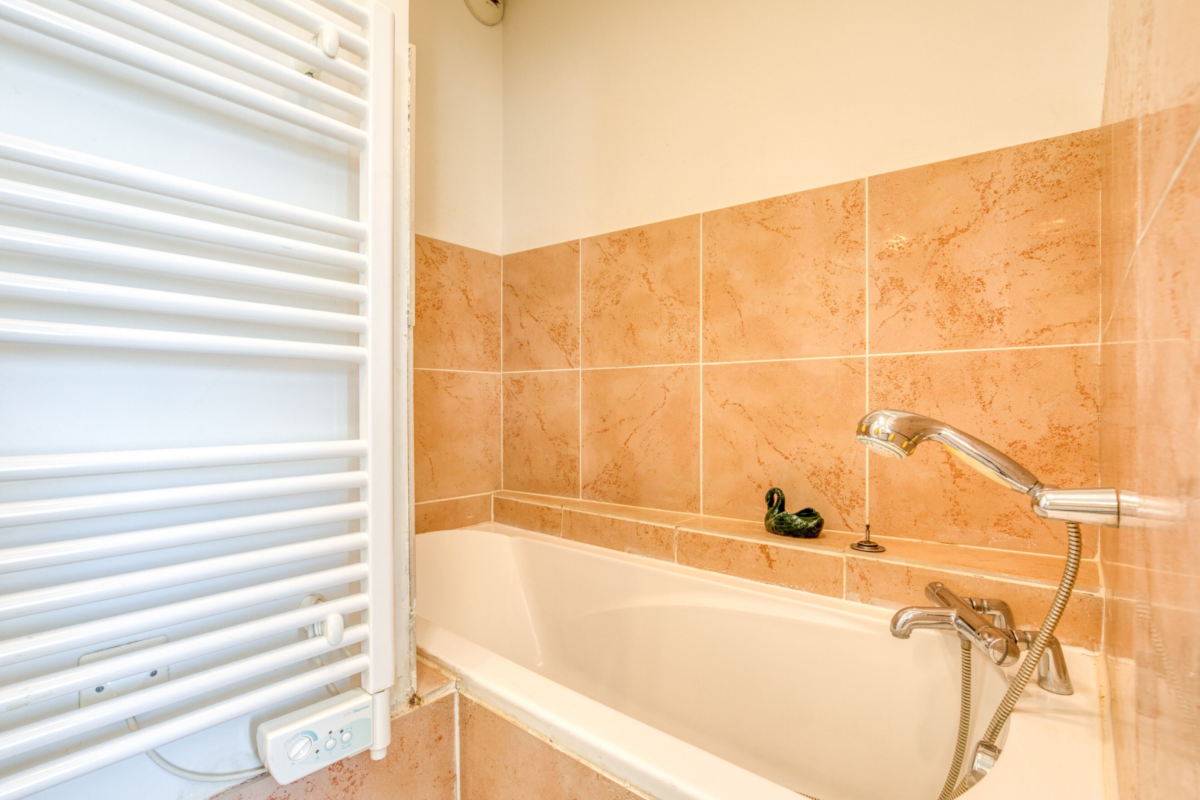 A bathroom with a bathtub, a shower, and a white radiator.