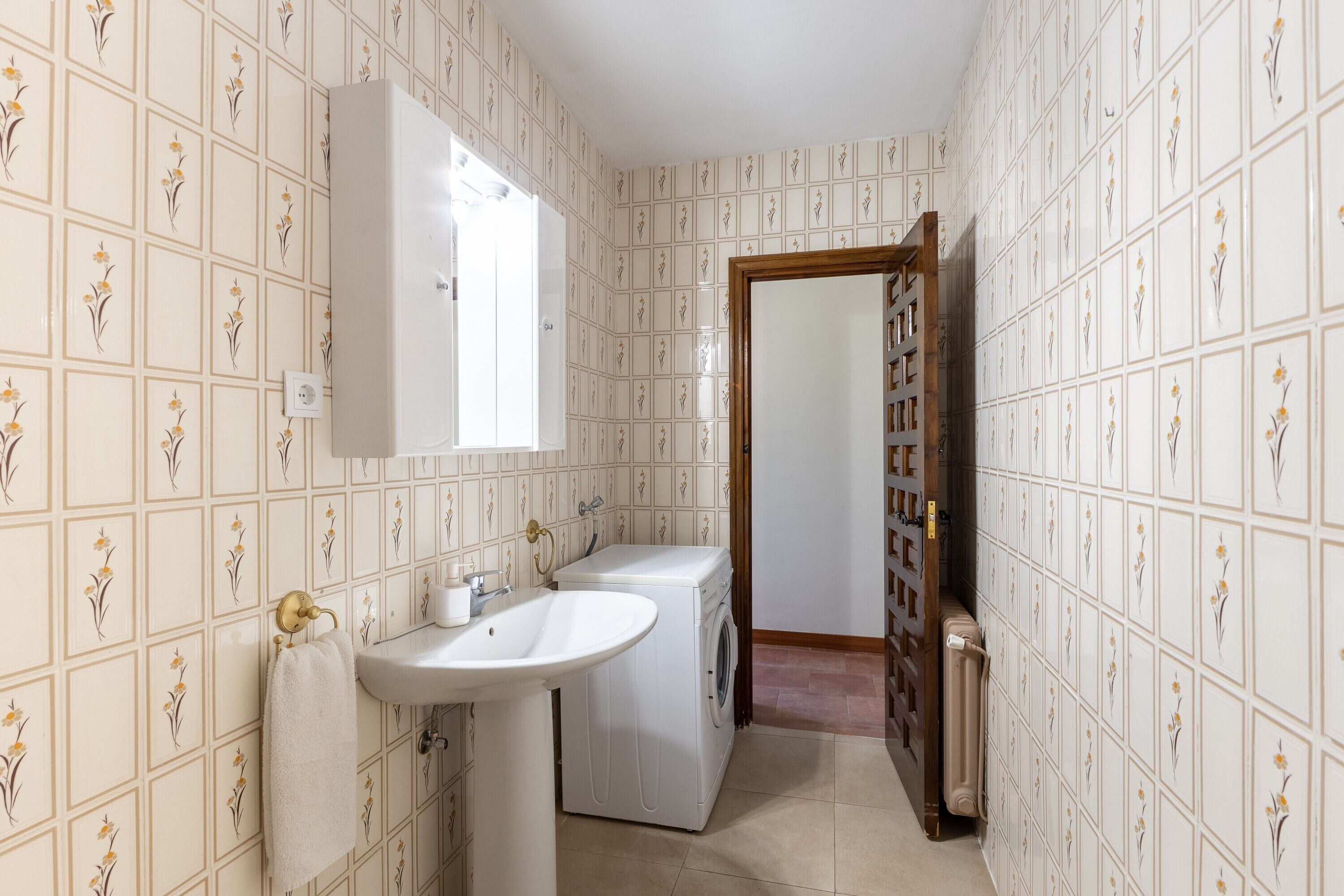 A bathroom with a sink, mirror, and washing machine.