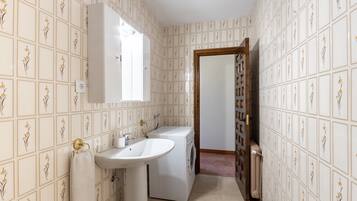 A bathroom with a sink, mirror, and washing machine.