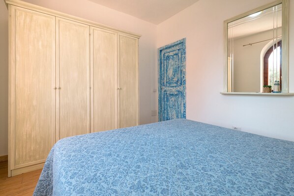 A bedroom with a bed, wardrobe, and a mirror.